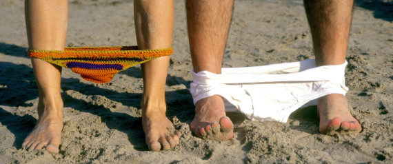 Man and woman drop their bathing suits at the beach.