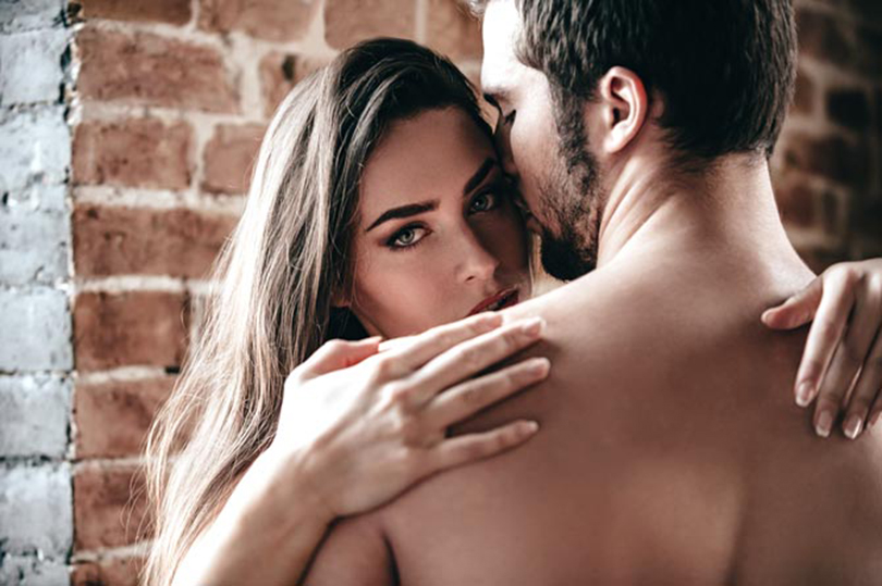 Close-up of beautiful young shirtless couple hugging while woman looking over shoulder of her boyfriend